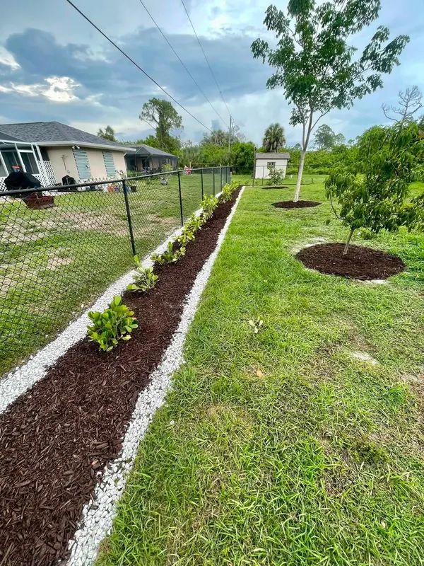 Long fence line bed with mulch and white rock edging