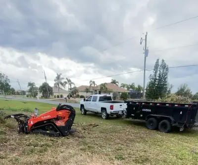 Mini skid steer, pickup and dump trailer on a cleanup job