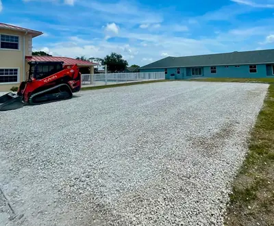 Skid steer beside a freshly spread gravel parking area