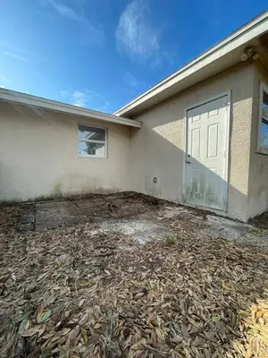 Back patio covered in leaves and dirt before cleaning